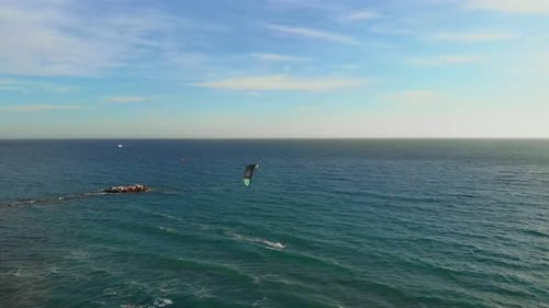 Male athlete kite boarding on waves in sea at windy day
