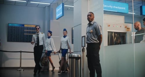 Airport Terminal Airline Pilot and Two Flight Attendants Walking Passing By Security Officer