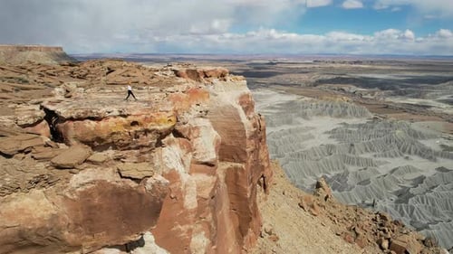Drone Shot of Woman Walking on The Edge of Cliff Above Deep Desert Canyon and Abyss