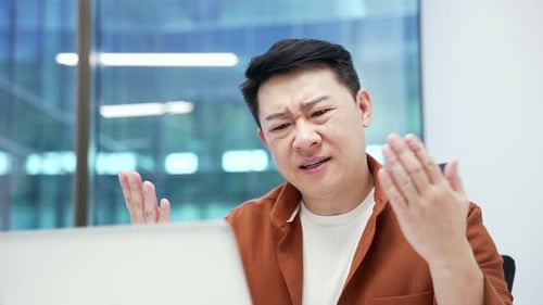 Frustrated Young Adult Using Laptop in Modern Office