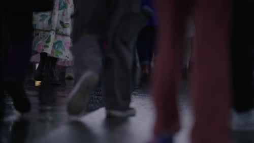 A Bustling Urban Crowd is Actively Walking Along a Rainy Street in a Lively Cityscape