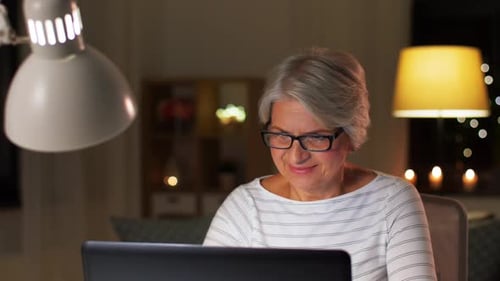 Senior woman using laptop at night in home