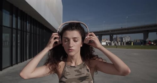 Stylish Woman Removes Headphones in Urban Setting