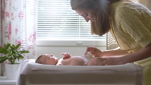 Loving Mother Changing Baby Diaper at Home