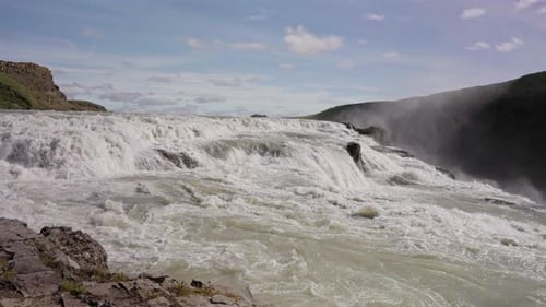 Rushing Waterfall Cascading Over Rocks on a Sunny Day