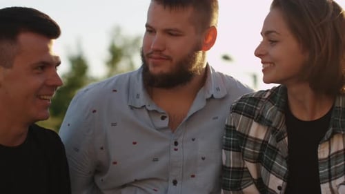 Three Young Adults Chat in Warm Golden Sunlight