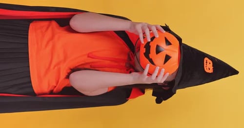 Girl in Witch Costume Holding Jack-o-Lantern