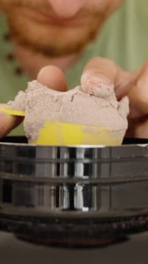 Vertical video. Man Scooping Protein Powder with a Measuring Spoon from a Large Jar and Tapping Off
