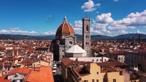 Drone rising high overlooking Cathedral of Santa Maria del Fiore and city on a sunny day in Florence