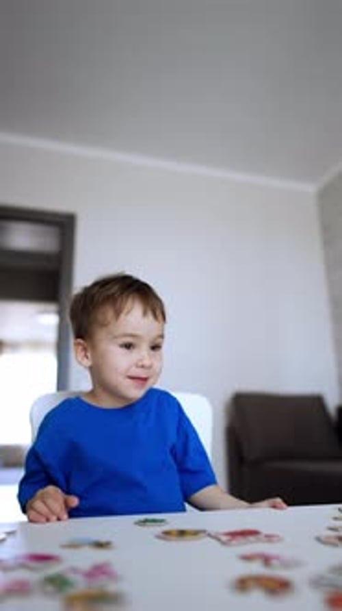 Hermoso bebé caucásico sentado en el escritorio jugando un juego. Un niño alegre colecciona rompecabezas.