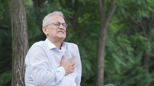 Man with chest pain is in the park. Man with health problem.