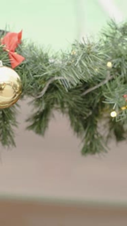 Vertical video. Christmas tree ornaments hanging on the branches of the house's eaves.