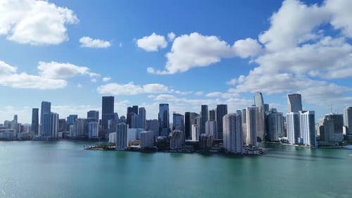 Drone View of Downtown Miami Skyline with Tall Skyscrapers and Turquoise Ocean Under Cloudy Sky