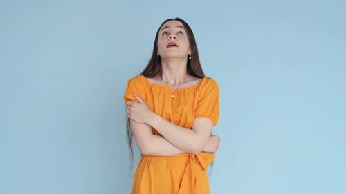 Feelling dreamy. Woman in yellow clothes standing in the studio and showing emotions