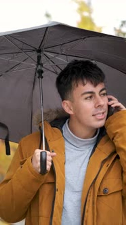 Young Adult Chatting on Phone Under Umbrella
