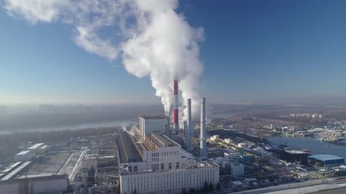 Aerial establishing shot of a coal-fired heating power station with thick white smoke coming from th