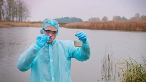 Researcher Examining Water Sample Near Lake
