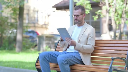Man Video Conferencing on Tablet in the Park