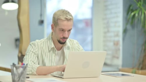 Young Man Gives Thumbs Up at Laptop