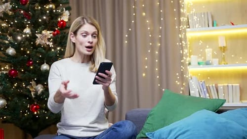 Woman Celebrates Good News on Phone at Christmas