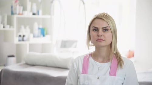 Woman in White Medical Coat Looks at Camera