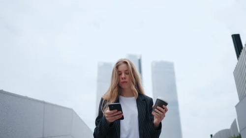 Woman Using Smartphone with Coffee in City