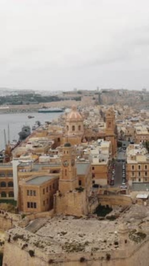 Aerial - senglea basilica rises above malta's grand harbour rooftops vertical