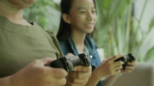 Teen Girl and Adult Playing Video Games at Home