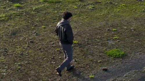 Young Lonely Man Walking On Lake Shore On Sunny Day. orbiting drone shot