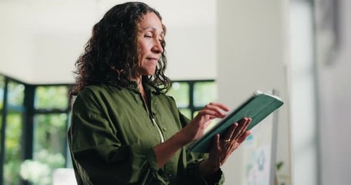 Creative, mature woman and tablet in office for research, proofreading and update draft