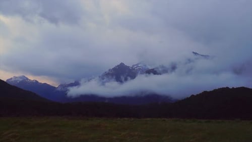Wolken bewegen sich um die hohen Berge, während die Nächte hereinbrechen. Zeitraffer