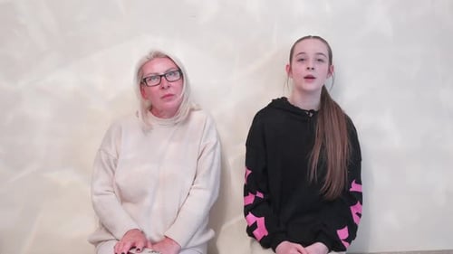 Woman and Teenager Sitting Against a Wall