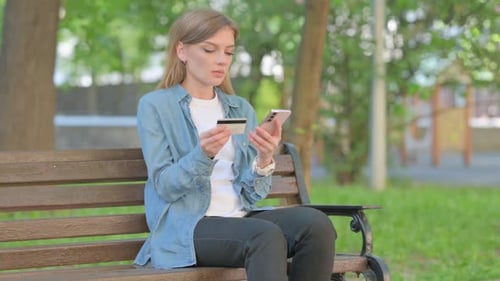 Woman Online Shopping with Credit Card in Park