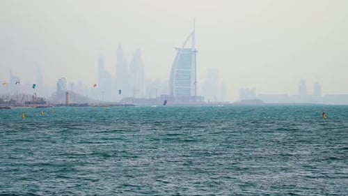 Steady dolly in shot of the Burj Al Arab hotel and the Dubai Skyline with kite surfers in the foregr