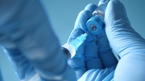 Gloved Hand Draws Vaccine from Vial with Syringe