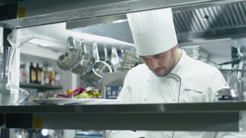 Professional chef in a commercial kitchen in a restaurant or hotel is slicing green vegetables.