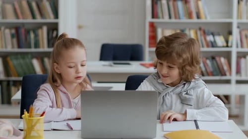 Süße kleine Jungen und Mädchen diskutieren über schwierige Testfragen, wählen eine Antwort aus und genießen Erfolg