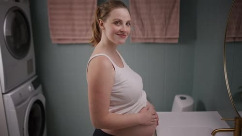 Une future mère chérit la bosse de son bébé dans la salle de bain