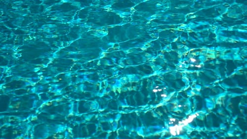 Background of Blue Water in a Swimming Pool with Sun Glare From the Waves