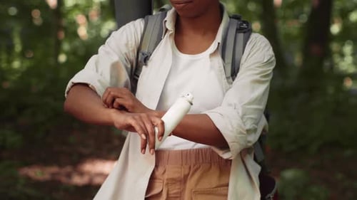 Woman Applying Insect Repellent While Hiking in a Forest During Daytime
