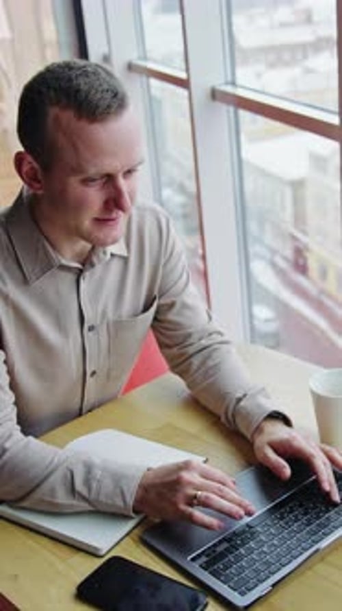 Young Adult Working on Laptop by Bright Window
