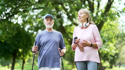 Happy active senior couple walking after workout in urban city park. Mature gray haired retired