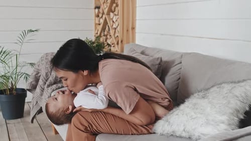 Woman Plays Gently with Infant on Couch