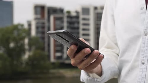 A Man Works on a Smartphone Closeup on the Hand and the Phone