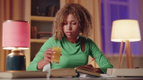 A Young Woman is Deeply Focused on Her Studying in a Comfortable Room with Soft Lighting