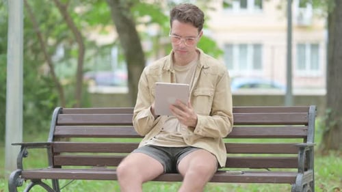 Man Using Tablet on Park Bench