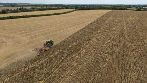 Aerial view of tractor tilling field, United Kingdom.