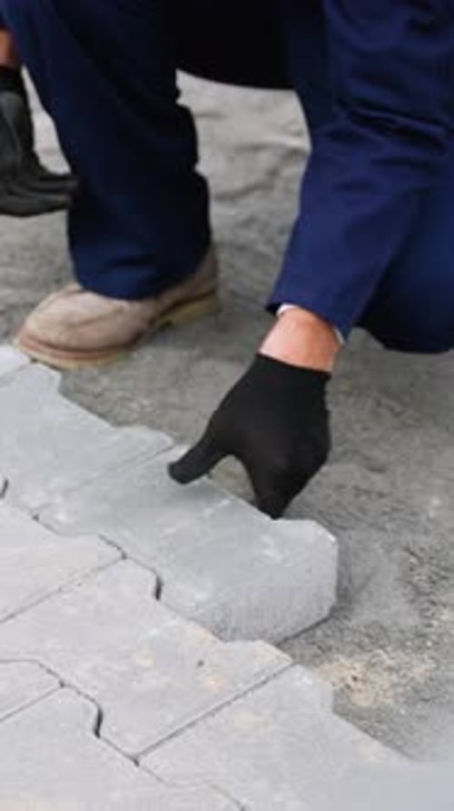 Worker Installing Paving Stones with Mallet and Level Tool