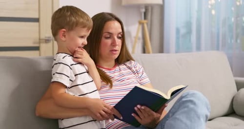 Woman Reading to Child on Couch Indoors