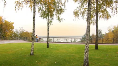 Long Shot of a Woman Riding a Ladies Bike with Balloons in a Park in Autumn
